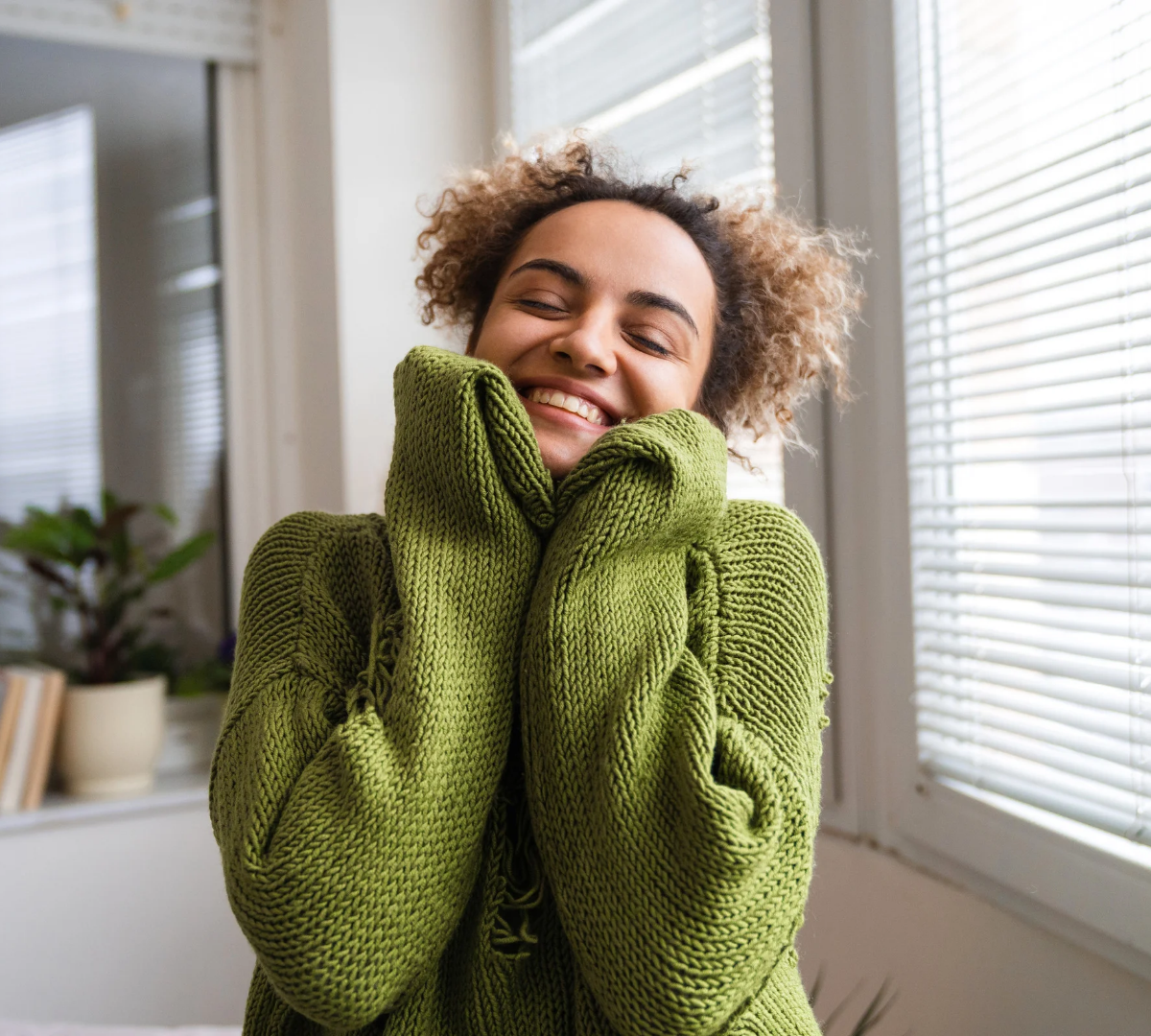 Woman is an oversized green cardigan. She looks happy and content.